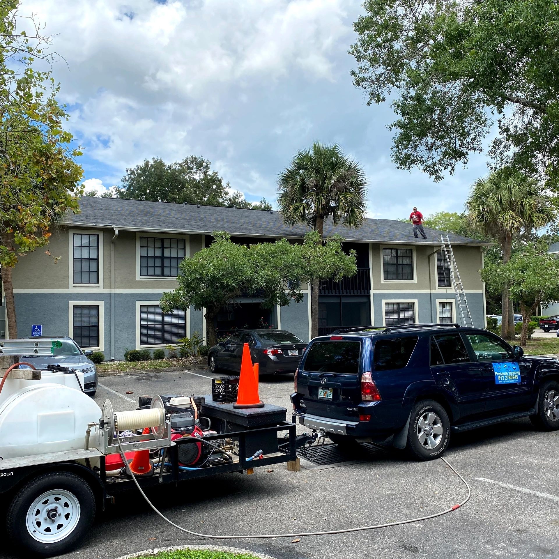 Worker pressure washing heavy machinery on site